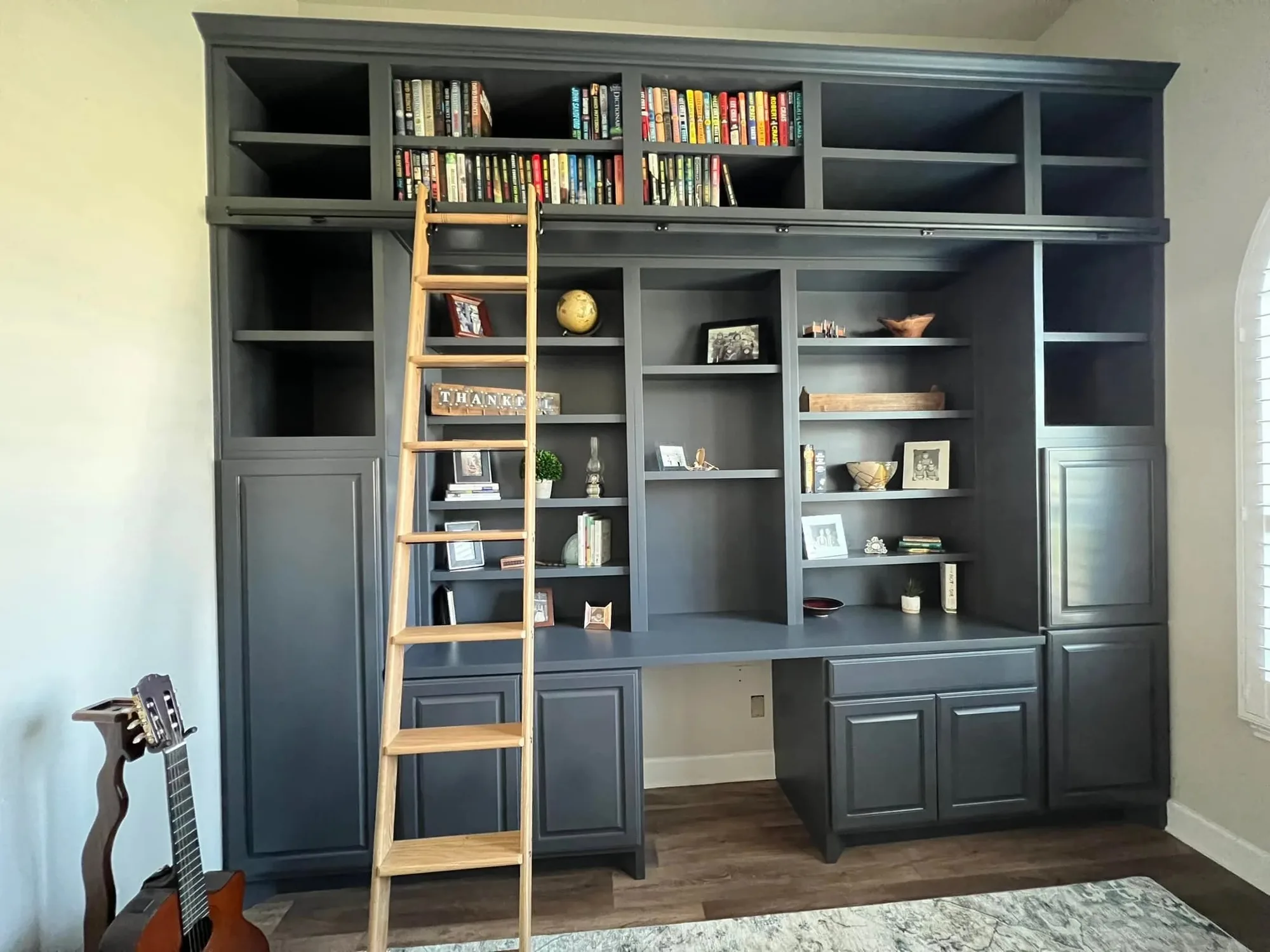 Built-in library shelving with a rolling ladder and desk