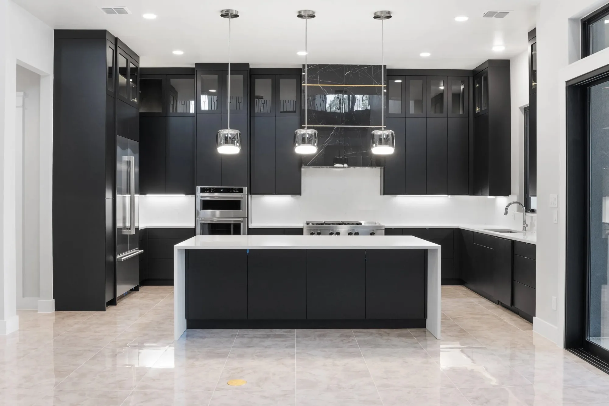 A modern black kitchen with a large island built by 405 Custom Cabinetry in San Antonio