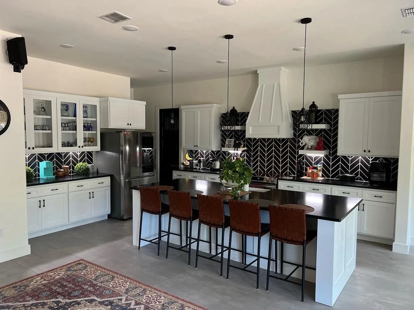 Shaker kitchen cabinets with a herringbone backsplash and island seating
